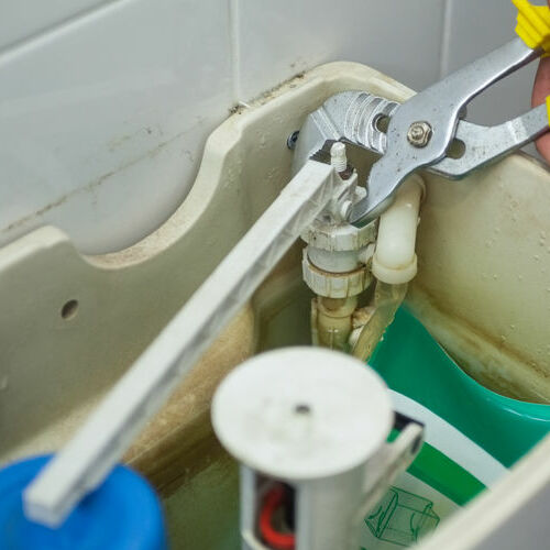 A Plumber Works on a Toilet.