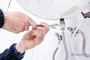 A Plumber Adjusts the Fittings on an Electric Water Heater